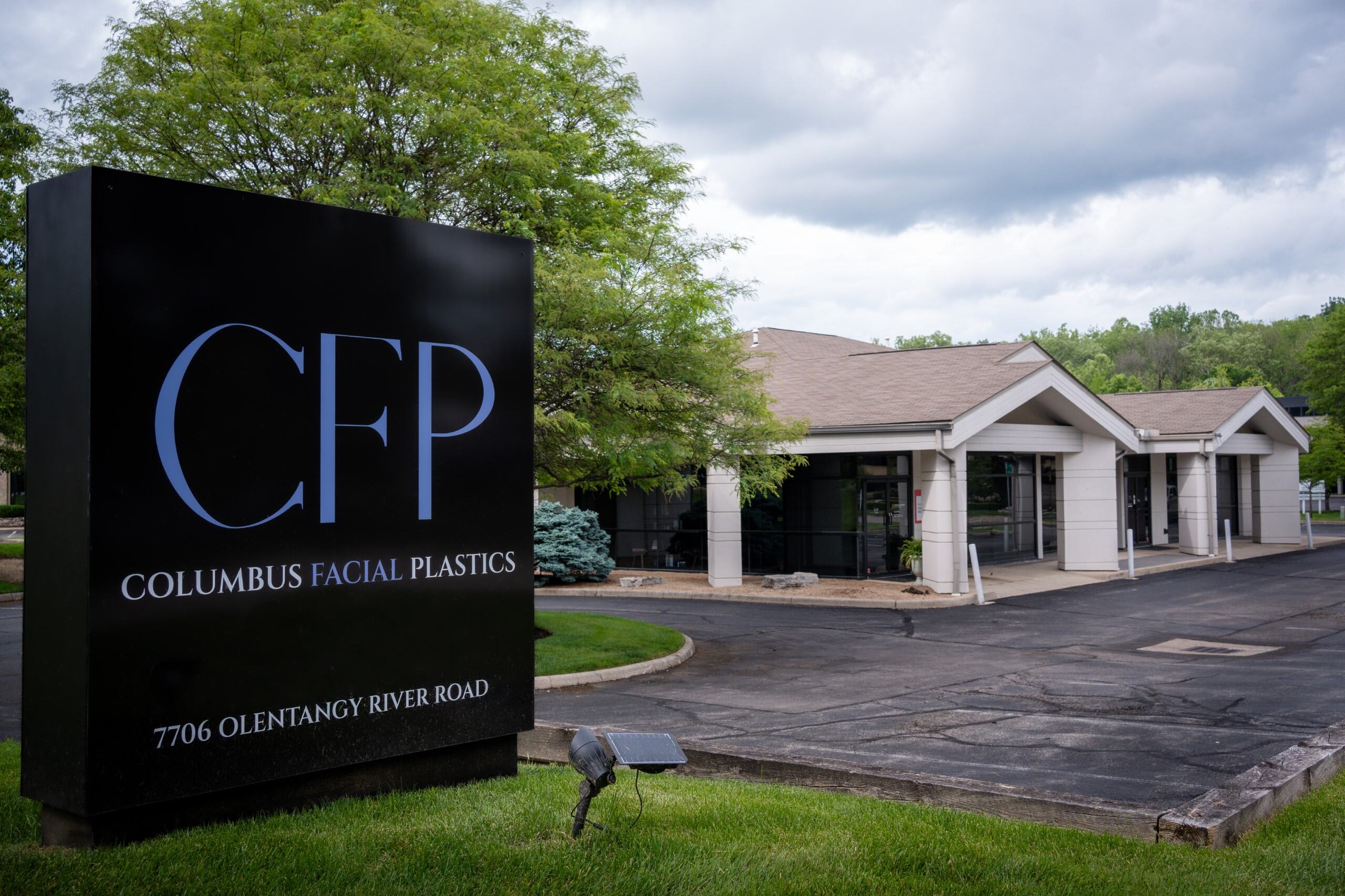 A sign reads "CFP, Columbus Facial Plastics." Behind, a building is seen.